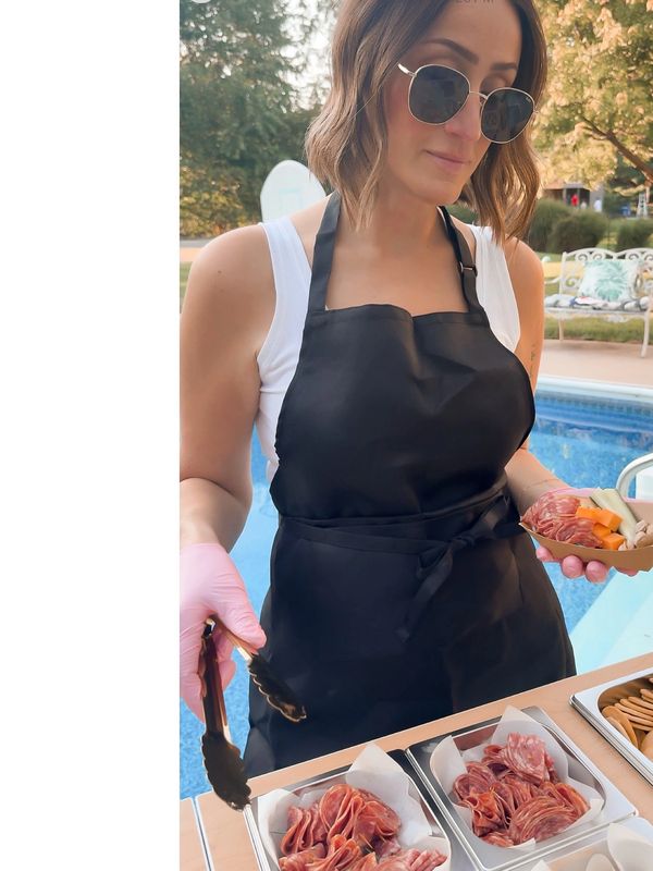 Woman in black apron holding meat slices by a pool.