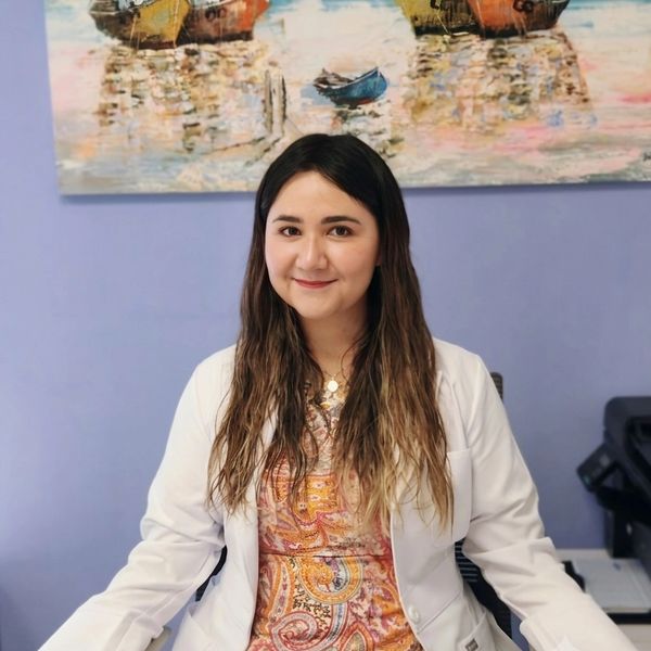 Mujer sonriente con bata blanca en oficina.