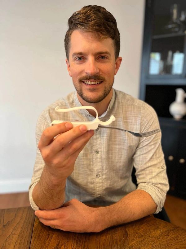 Owner of the MagnaCuff Andrew Flint holding a white MagnaCuff with a fork inserted into it
