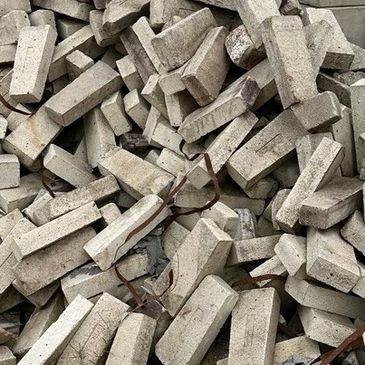 Pile of concrete bricks with rusted metal rods outdoors.