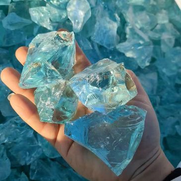 Hand holding large, translucent blue ice-like crystals.