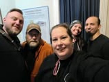 A group of five friends smiling for a selfie indoors.