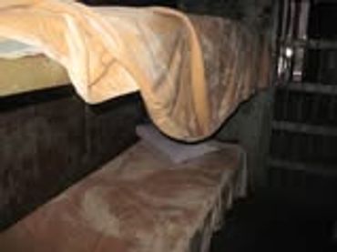 A simple, worn-out bed in a dimly lit room.