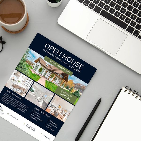 A computer desktop with a laptop, coffee cup, reading glasses, stationary and an open house flyer