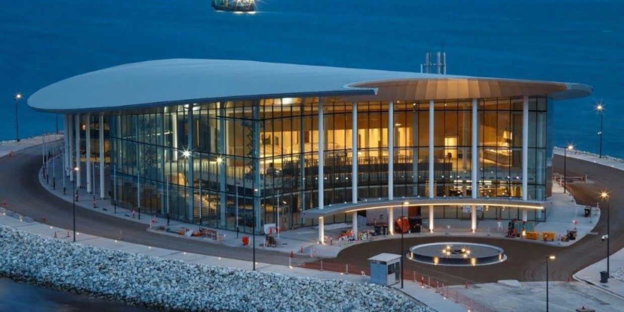 Modern waterfront building with extensive glass walls and curved roof.