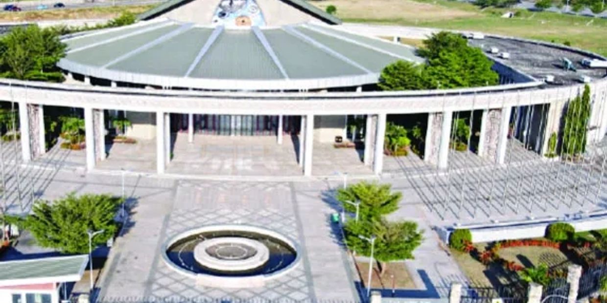 Aerial view of a modern circular building with a large open courtyard and fountain.