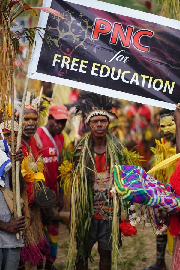 Group holding a PNC banner advocating free education, dressed in traditional attire.