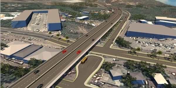 Aerial view of a highway interchange with vehicles and buildings.