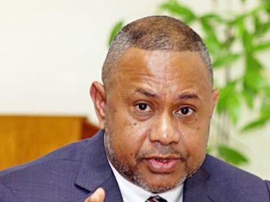 Man in a suit speaking with a serious expression.