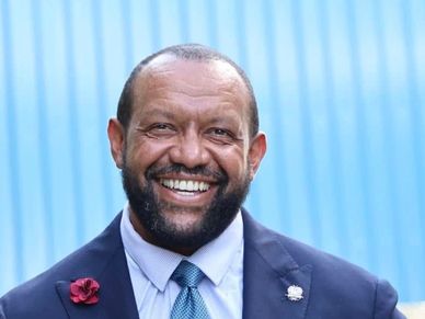 Smiling man in a suit with a blue background.