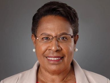Portrait of a smiling woman wearing glasses and pearl earrings.