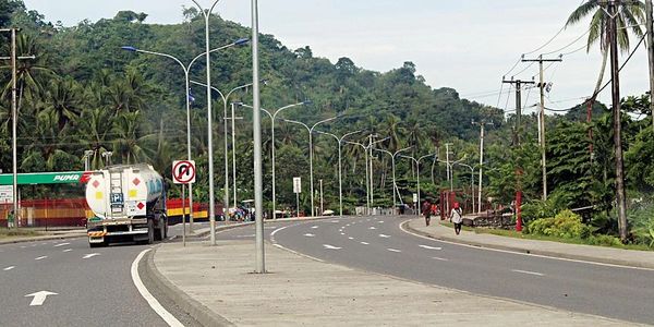 A curved highway surrounded by greenery and street lamps under a clear sky.