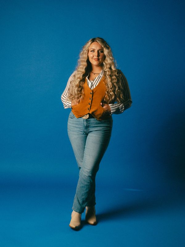 Woman with long blonde hair in casual vintage outfit.