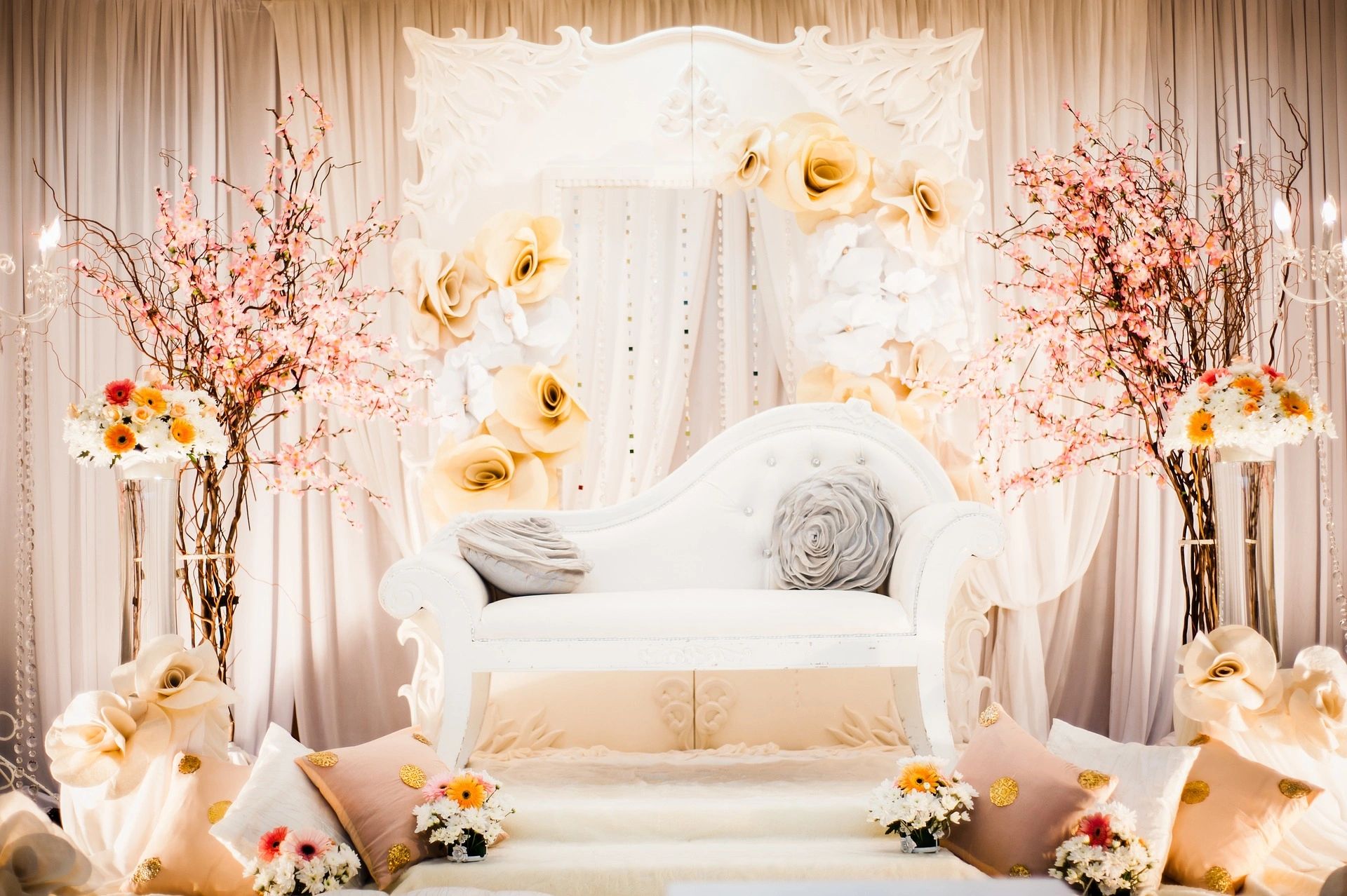 Elegant white and beige floral wedding stage with a vintage sofa.