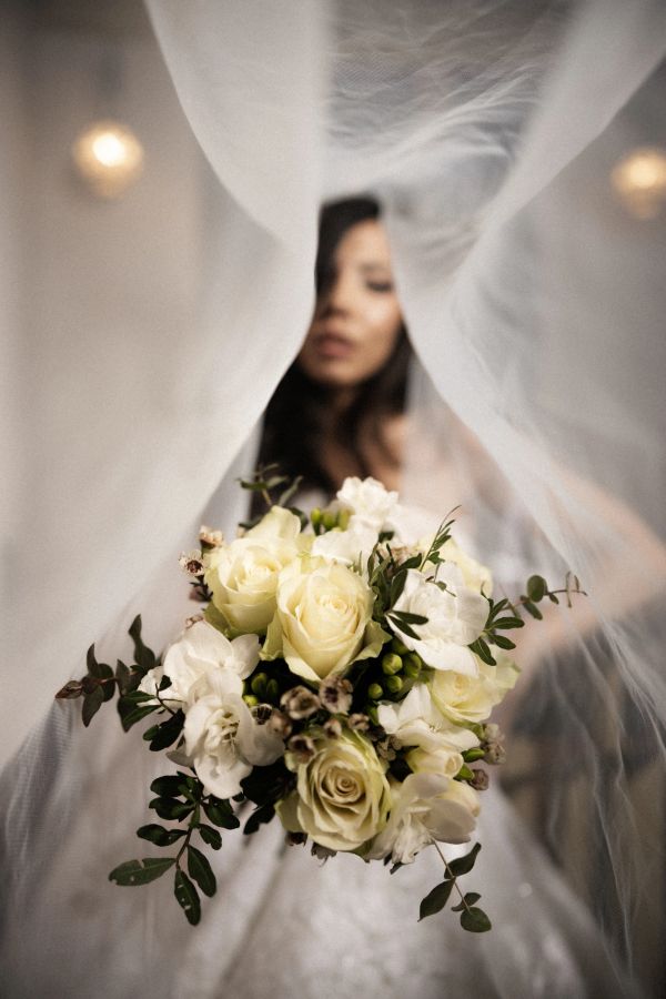 Bridal bouquet of white roses framed by a flowing veil.