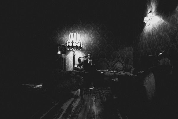 A person sitting in a dimly lit vintage room with classic furniture and lamps.