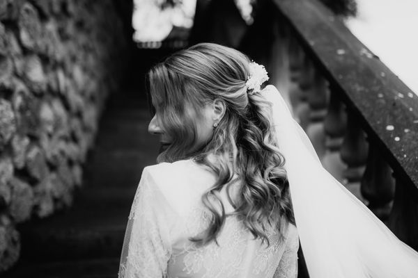 Black and white photo of a bride with wavy hair and veil on steps.