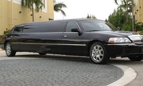 Black luxury stretch limousine parked on a curved driveway.
