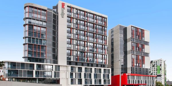 Modern multi-story building with red accents under clear blue sky.