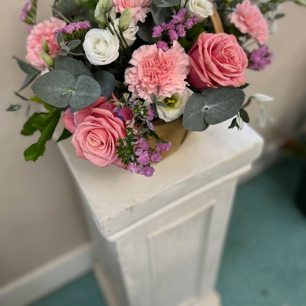 Pink and white flower arrangement on a white plinth
