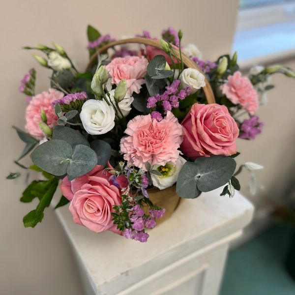 Pink and white flower arrangement on a white plinth
