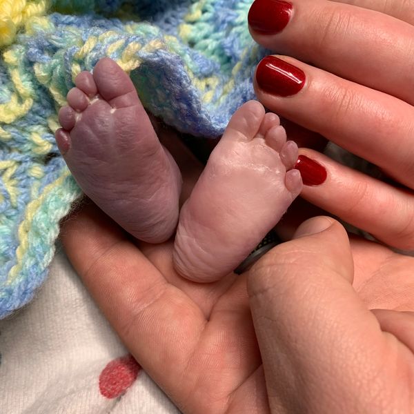 Photograph of Benji’s feet and his parents’ hands 