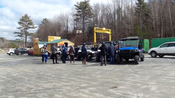 Group of people near utility vehicles in a parking area.