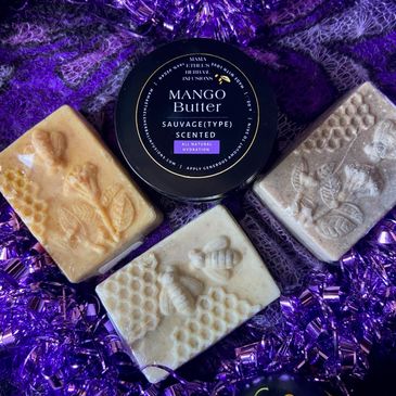 Three decorative soaps and a tin of mango butter on purple fabric.