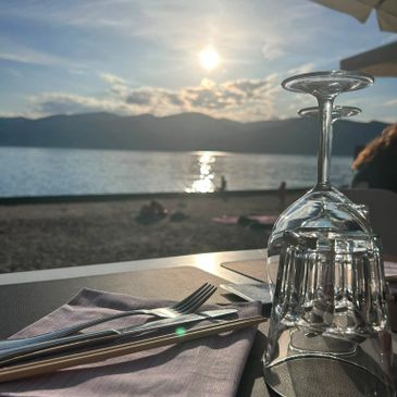Upside-down wine glasses and cutlery set by the beach at sunset.