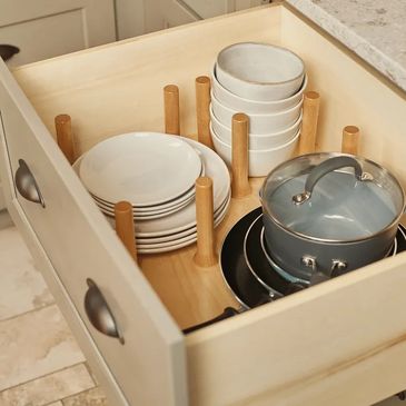 Organized kitchen drawer with plates, bowls, and pots separated by wooden dividers.