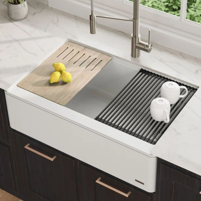 Modern kitchen sink with wooden and metal drying racks holding lemons and cups.