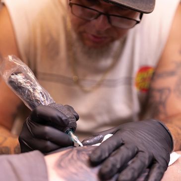 Tattoo artist focused on inking a detailed design on a client's skin.