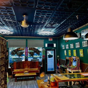 Tattoo shop interior with vibrant art, arcade games, and cozy seating.