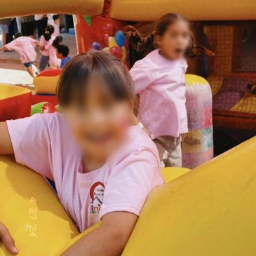 Niñas jugando en un parque inflable con camisetas rosas.