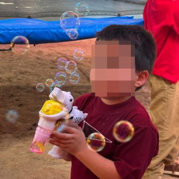 Niño jugando con pistola de burbujas al aire libre.