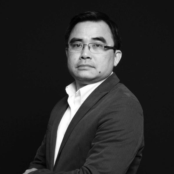 Confident man in glasses and suit posing against black background.