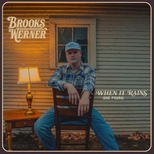 Brooks Werner's album cover for 'When It Rains (She Pours)' with a rustic, warm setting.