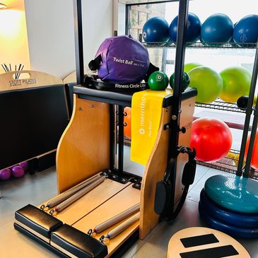 Pilates reformer machine with fitness accessories in a bright studio.