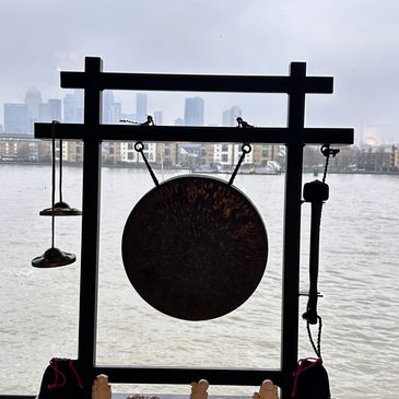 A decorative gong set with figurines against a city river backdrop.