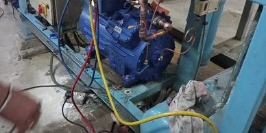 Industrial refrigeration compressor setup with gauges and control panel.
