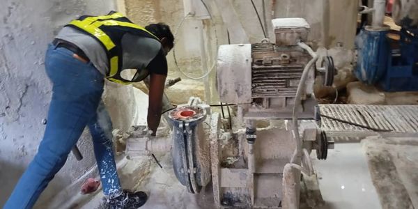 Worker repairing industrial machinery in a dusty environment.