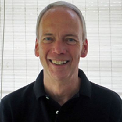 Head and shoulders of George Lawrence wearing a black polo shirt and smiling.