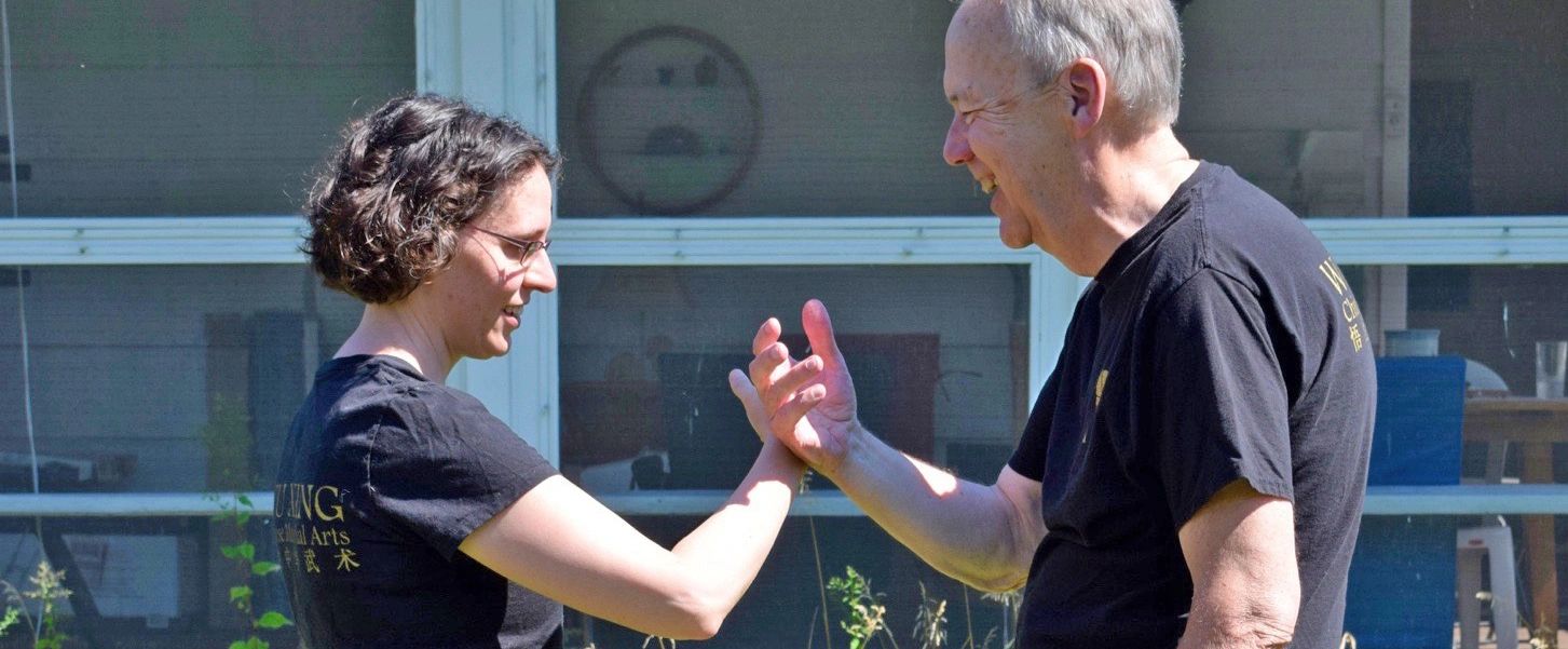 Woman and man practice tai chi push hands.