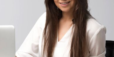 Smiling woman with long hair at a desk.