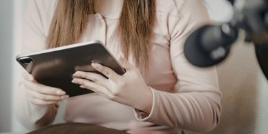 Person holding a tablet in front of a microphone.