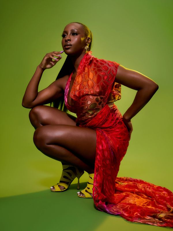 Woman in a vibrant red dress posing with a green background.
