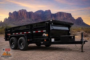Black dump trailer against a mountain backdrop at sunset.