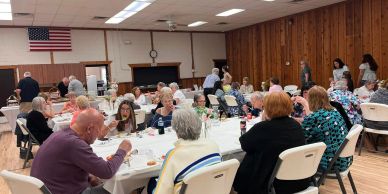 Community gathering with people dining in a hall.