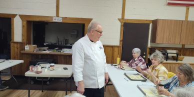 Chef talking to elderly women at a table.