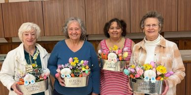 Four elderly women holding flower and Easter decorations.
